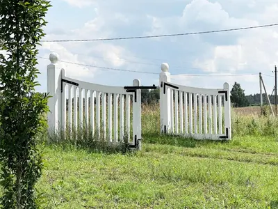 a white fence in the grass in a field at Lake Garden Villa in Sadžiūnai