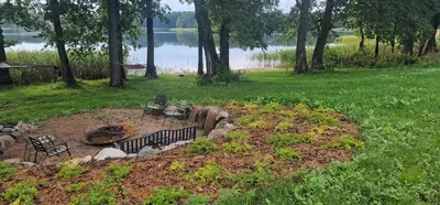 a fire pit in a yard next to a lake at Lake Garden Villa in Sadžiūnai
