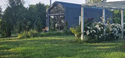 a garden with a blue building in the grass at Lake Garden Villa in Sadžiūnai
