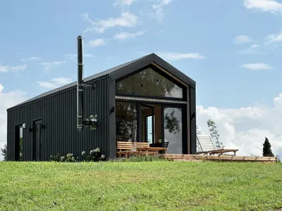 a black house on top of a grassy field at Lake Garden Villa in Sadžiūnai