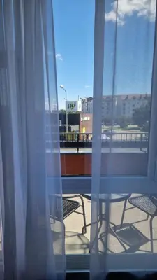 a window with a view of a balcony with tables and chairs at Apartamentai Vilnius Lazdynėliai in Vilnius