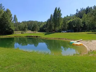 a small pond with a boat in the middle of a field at Kabakėlio slėnis in Kabakelis