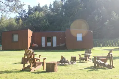 a cabin in a field with chairs in front of it at Kabakėlio slėnis in Kabakelis
