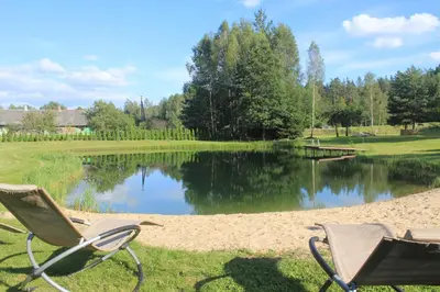 two chairs sitting in the grass next to a lake at Kabakėlio slėnis in Kabakelis