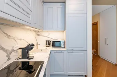 a kitchen with white cabinets and a sink and a microwave at Sun Sonata Apartments 3 in Druskininkai