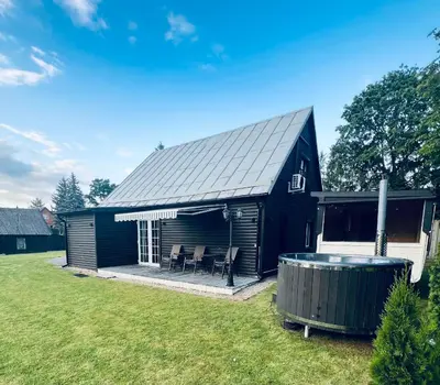 a black shed with a hot tub in the yard at Už Karvelius - Sodyba Biržų mieste in Biržai