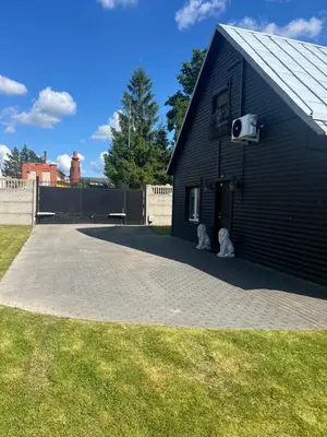 two dogs sitting outside of a black building at Už Karvelius - Sodyba Biržų mieste in Biržai