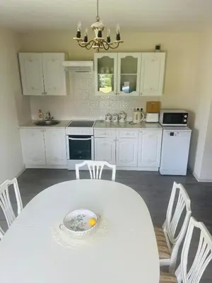 a white kitchen with a white table and chairs at Už Karvelius - Sodyba Biržų mieste in Biržai