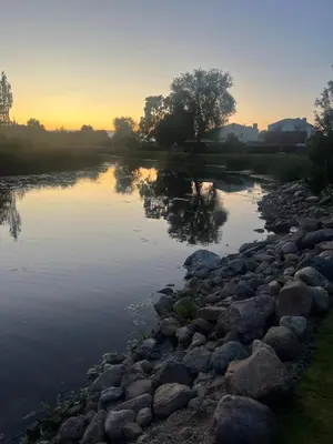 a river with rocks and the sunset in the background at Už Karvelius - Sodyba Biržų mieste in Biržai
