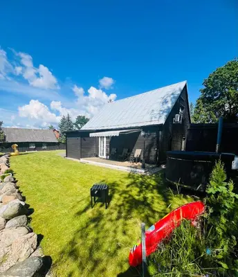 a black barn with a grass yard in front of it at Už Karvelius - Sodyba Biržų mieste in Biržai