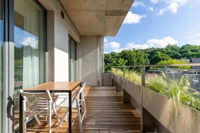 a balcony with a wooden table and chairs on a building at Light- Filled Flat with Balcony in a Heart of Kaunas in Kaunas