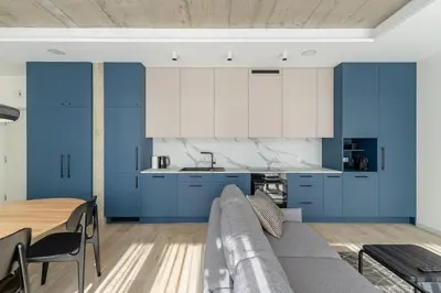 a kitchen with blue and white cabinets and a couch at Light- Filled Flat with Balcony in a Heart of Kaunas in Kaunas