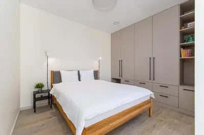a white bedroom with a large bed and white cabinets at Light- Filled Flat with Balcony in a Heart of Kaunas in Kaunas