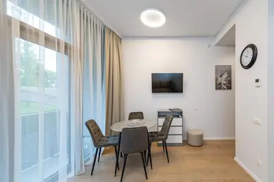 a dining room with a table and chairs and a window at Sun Sonata Apartments 1 in Druskininkai