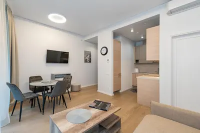 a living room with a table and a kitchen at Sun Sonata Apartments 1 in Druskininkai