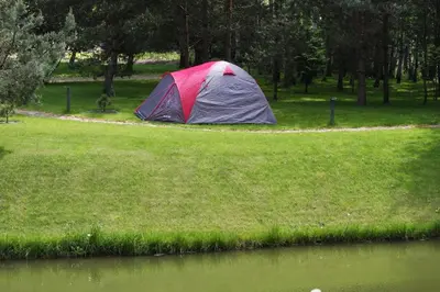 a tent in a field next to a body of water at Kernavės Pajauta in Kernavė