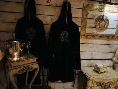 two black robes hanging on a wall next to a table at Apartment Host 4 in Kaunas