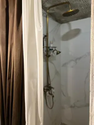 a shower with a shower curtain in a bathroom at Apartment Host 4 in Kaunas