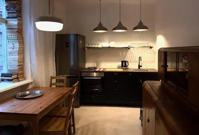 a kitchen with a wooden table and a kitchen with black appliances at Uzupio4 Old Town House in Vilnius