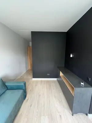 a living room with a blue couch and a black wall at Apartamentai 1 in Raseiniai