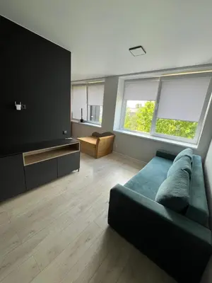 a living room with a green couch and two windows at Apartamentai 1 in Raseiniai