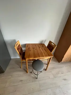 a wooden table and two chairs in a room at Apartamentai 1 in Raseiniai
