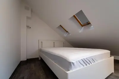 a white bedroom with a bed in the attic at Marvelės 30 Lofts in Kaunas