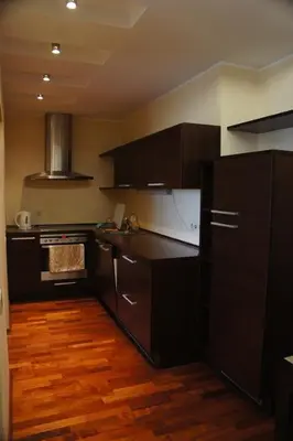 a kitchen with black cabinets and a wooden floor at Lyra Apartments in Druskininkai