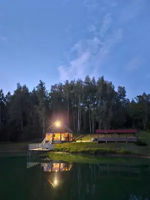 a cabin on the shore of a lake at night at Sodyba Prie Maluno in Salakas