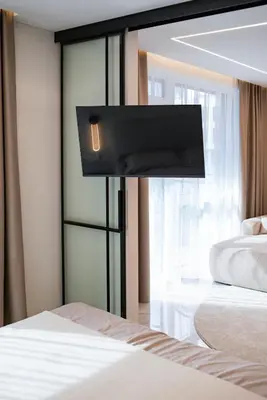a bedroom with a bed with a tv on the wall at Stylish apartment next to the center in Vilnius