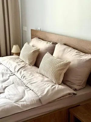 a bed with white sheets and pillows on it at Lake Town apartments in Zarasai