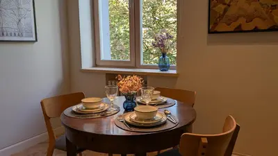 a dining room table with plates and cups and chairs at Avenue Apartments in Kaunas