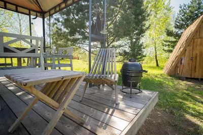 a grill and two chairs on a wooden deck at Briedžio sapnas in Sudervė