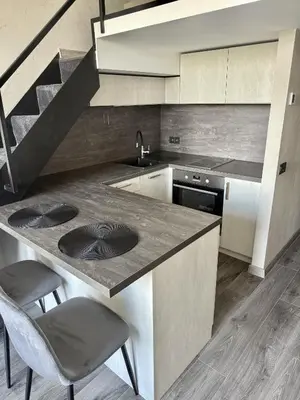 a kitchen with a sink and a counter with two chairs at Urban Breeze Kaunas in Kaunas