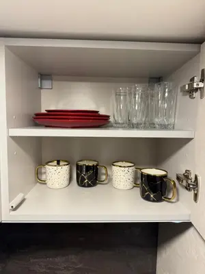 a cupboard with a row of mugs and plates at Urban Breeze Kaunas in Kaunas