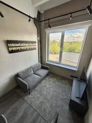 a living room with a couch and a large window at Urban Breeze Kaunas in Kaunas