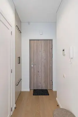 a hallway with a wooden door in a white room at Saulės Sonata apartamentai 5 in Druskininkai