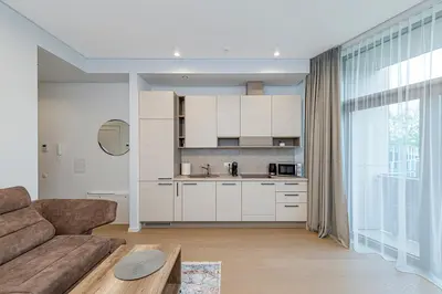 a living room with a couch and a kitchen at Saulės Sonata apartamentai 5 in Druskininkai