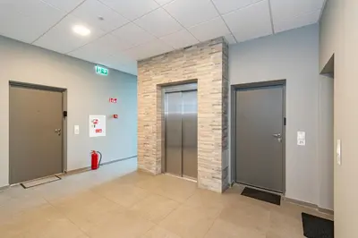 a lobby with two elevators and a brick wall at Saulės Sonata apartamentai 5 in Druskininkai