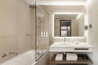 a bathroom with a tub and a sink and a mirror at AC Hotel by Marriott Vilnius in Vilnius