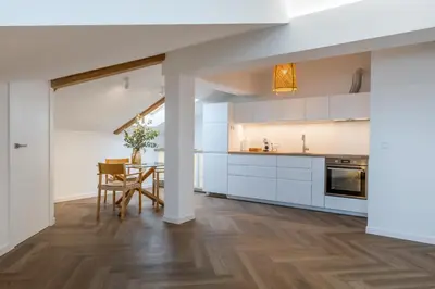 a kitchen with white cabinets and a dining room with a table at Griunvaldo apartamentai in Kaunas