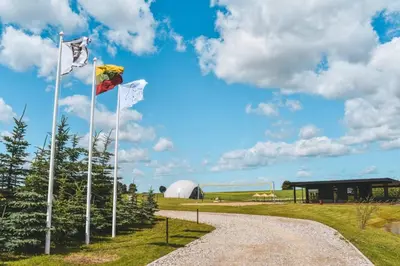 two flags on a gravel road in front of a building at Vilkiškių Karpis Glamping in Vilionys