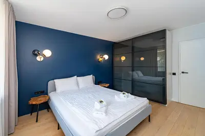 a bedroom with a large white bed and a blue wall at 2-BD Apartment Winery by Polo Apartments in Kaunas