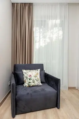 a couch with a pillow on it in front of a window at Jaukus poilsis Birštone in Birštonas