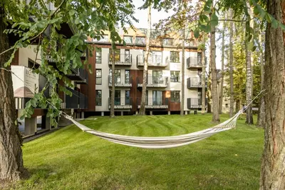 a hammock in a park in front of a building at Jaukus poilsis Birštone in Birštonas