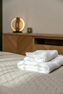 a stack of white towels sitting on a bed at Jaukus poilsis Birštone in Birštonas
