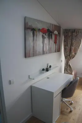 a white desk with a chair and a painting of umbrellas at Central Kaunas Apartment in Kaunas