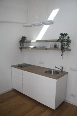 a white kitchen with a sink and a counter at Central Kaunas Apartment in Kaunas