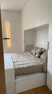 a white bedroom with a large bed and a lamp at Algirdo Sunlight Studio in Vilnius
