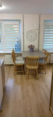a dining room with a table and chairs and a clock at Gimnazijos apartamentai in Biržai